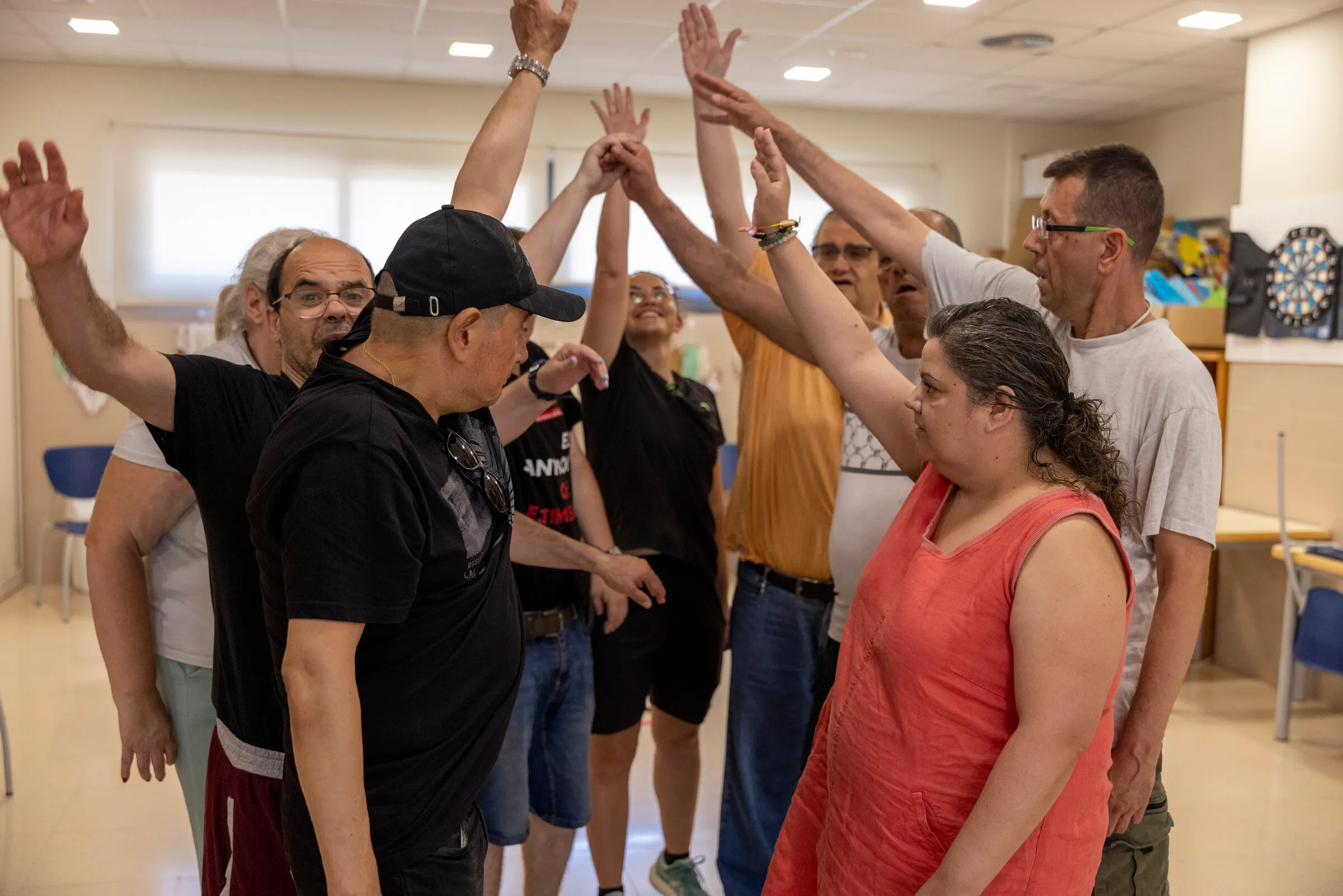 Un grup de persones ajunta les mans enlaire en una sala de la Fundació Hospitalàries Sant Boi.